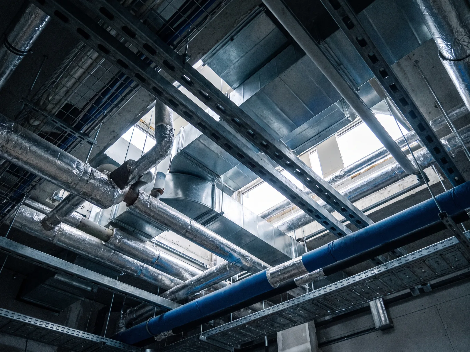 Cavedio tecnico affollato: canali, tubazioni e passerelle in un controsoffitto reale